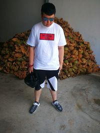 Man in sunglasses standing against heaped coconut peel