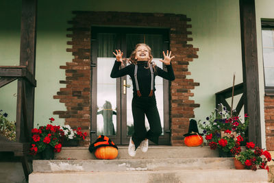 Little girl in carnival costume and make-up jumping and having fun on halloween, play and laugn