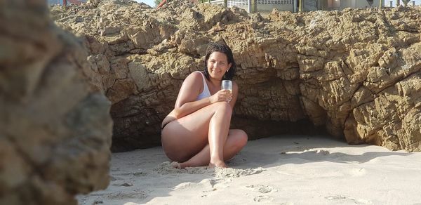 Portrait of young woman sitting on rock at beach