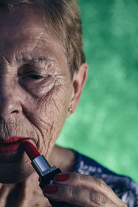 Mature woman in the foreground painting her lips in red
