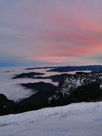 Scenic view of snow covered mountains against sky at sunset