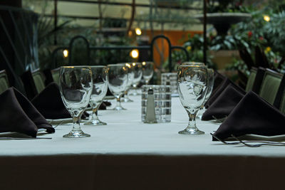 Close-up of wine glasses and napkins on plates at table in restaurant