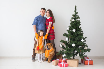 Full length of a woman with dog on christmas tree