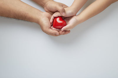 Midsection of man holding heart shape over white background