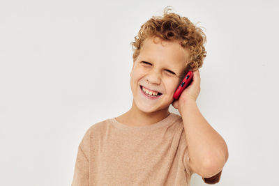 Portrait of smiling boy talking on phone against white background