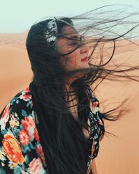 Young woman on sand at beach against sky