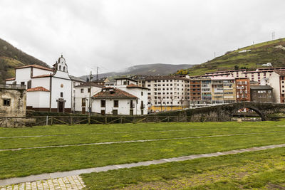 Houses by buildings in town against sky