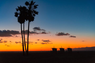 Silhouette palm trees on beach against sky during sunset