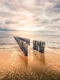 Wooden posts on beach against sky