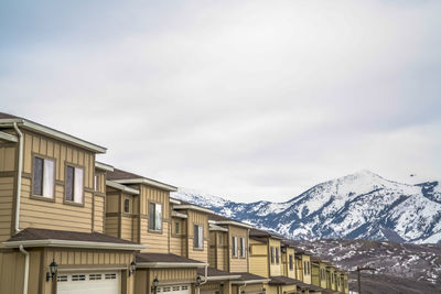 Low angle view of buildings against mountains during winter