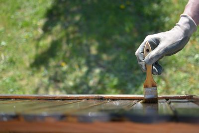 Close-up of man painting wood on field