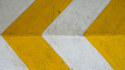 Close-up of yellow arrow sign on road