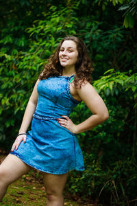 Portrait of smiling teenage girl with hand on hip standing at park