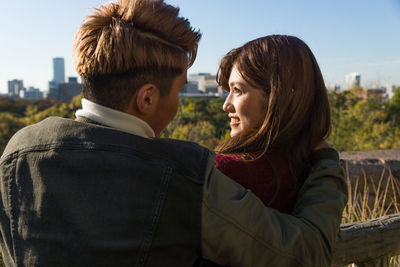 Young couple kissing against sky