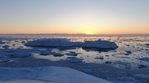 Scenic view of frozen lake against sky during sunset