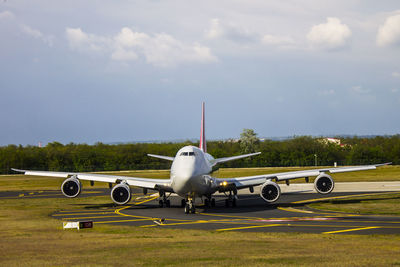 Airplane on airport runway against sky