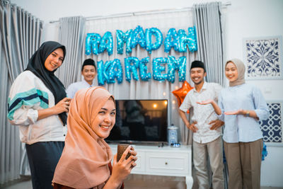 Portrait of female friends standing against wall