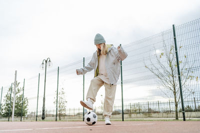 Happy teenage girl playing with soccer ball on playground