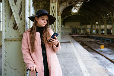 Beautiful young woman waiting for train at train station for travel in autumn.