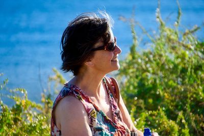 Woman wearing sunglasses against sea on sunny day