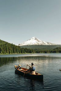 A father canoes with his daughter on trillium lake near mt. hood, or.