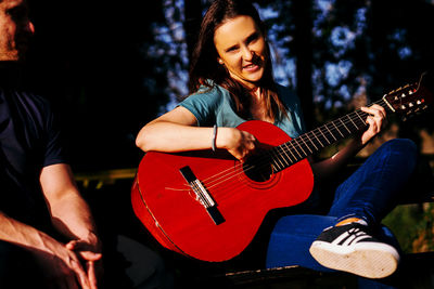 Portrait of woman playing guitar outdoors