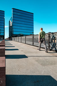 Man standing against blue sky in city