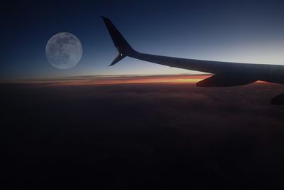 Airplane wing against sky during sunset