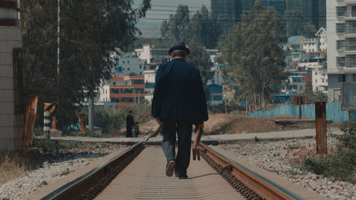 Rear view of man standing on railway tracks