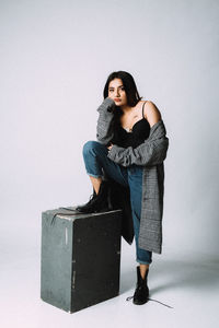 Portrait of young woman standing against white background