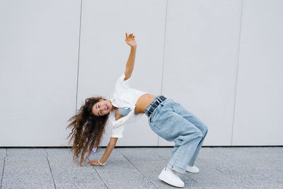Dynamic girl from generation alpha doing a backbend pose next to her skateboard, showcasing 