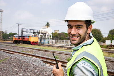 Portrait of smiling man standing on railroad track