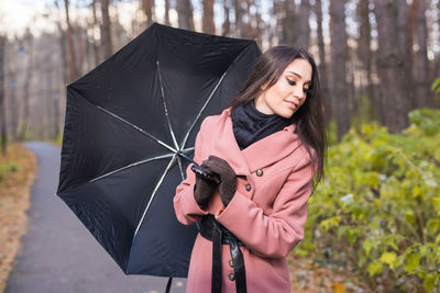 Young woman with umbrella standing in rain