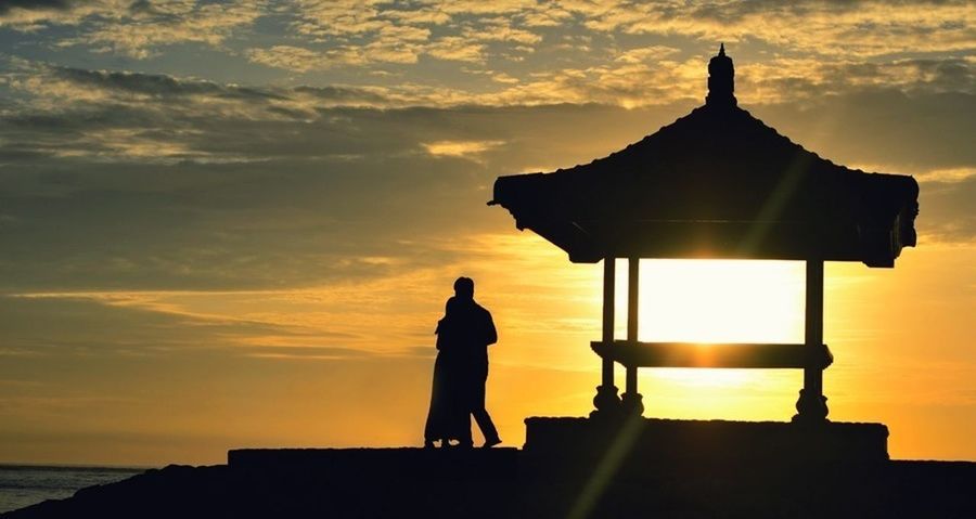 silhouette, sunset, sky, orange color, built structure, sea, standing, cloud - sky, architecture, building exterior, men, beauty in nature, water, lifestyles, scenics, spirituality, dusk, nature