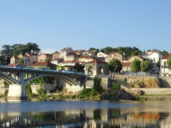 Bridge over river in town against clear blue sky