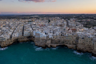 High angle view of townscape by sea against sky during sunset