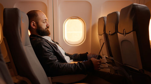 Side view of businessman sitting in airplane