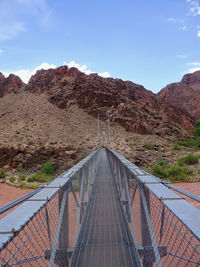 Footbridge over river against sky