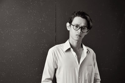 Portrait of young man standing against wall