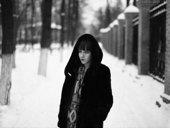 Thoughtful young woman in warm clothing standing outdoors