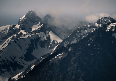 Snowcapped mountain peak surrounded by storm clouds.