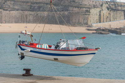 Fishing boats moored at sea shore against sky