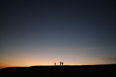Silhouette people standing on field against sky during sunset