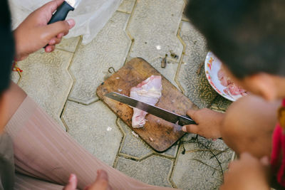 Cropped image of people cutting meat on footpath