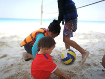 Boy with sisters playing volleyball at beach