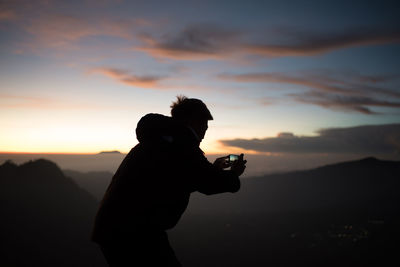 Silhouette man standing against sky during sunset