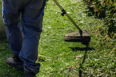 A gardener mows the lawn in his garden plot with a gasoline brush cutter