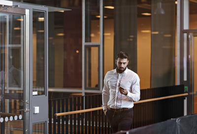 Young businessman using smart phone while walking in lobby