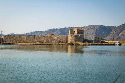 Buildings by sea against clear sky