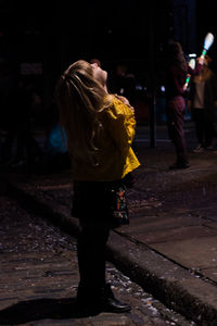 Rear view of woman walking on street at night